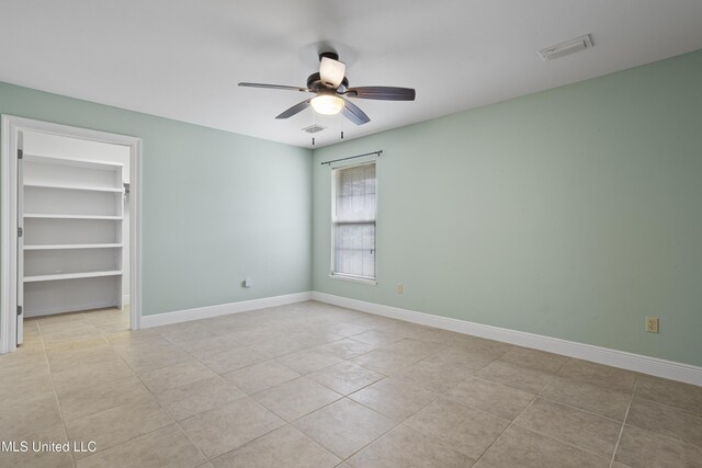 spare room featuring light tile patterned floors, baseboards, ceiling fan, and visible vents