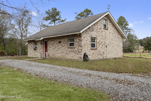 view of front of house featuring a front yard, brick siding, and roof with shingles