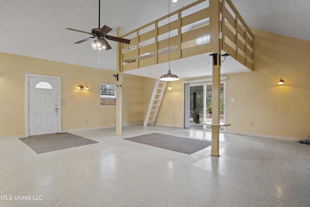 foyer entrance with baseboards, ceiling fan, and a towering ceiling