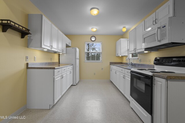 kitchen with light floors, a sink, baseboards, and white appliances