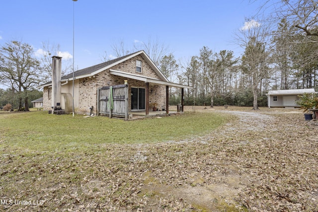 back of house with brick siding, a yard, and a chimney
