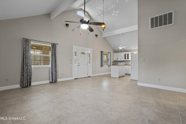 unfurnished living room with a ceiling fan, beam ceiling, a healthy amount of sunlight, and visible vents