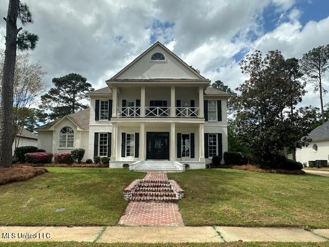 117 Peninsula Dr, Brandon, MS 39047 - greek revival house with a balcony, stucco siding, and a front lawn