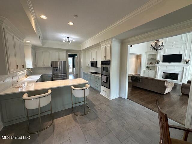 117 Peninsula Dr, Brandon, MS 39047 - kitchen with a peninsula, ornamental molding, open floor plan, black appliances, and an inviting chandelier