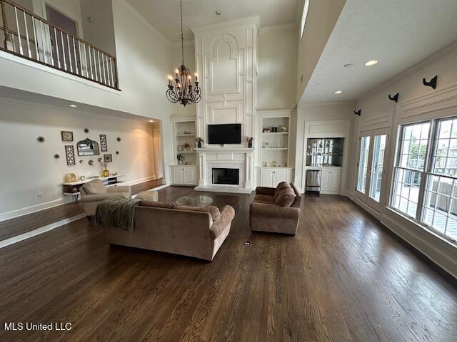 117 Peninsula Dr, Brandon, MS 39047 - living room with a fireplace, dark wood-style floors, a chandelier, and crown molding