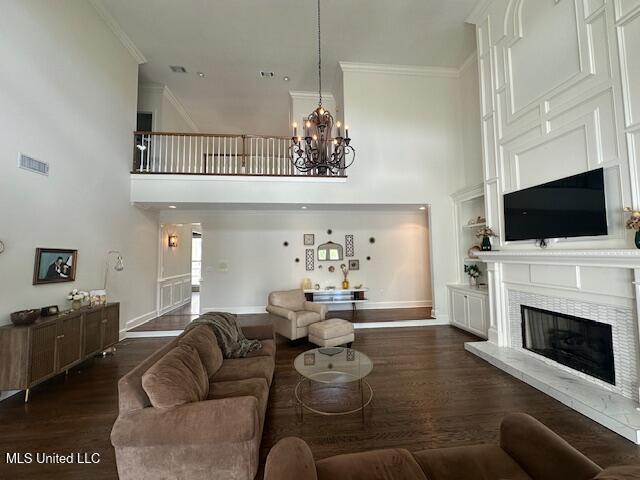 117 Peninsula Dr, Brandon, MS 39047 - living area with crown molding, baseboards, dark wood finished floors, a tiled fireplace, and a notable chandelier