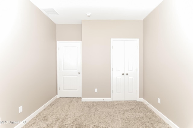 unfurnished bedroom featuring a closet, light colored carpet, and baseboards