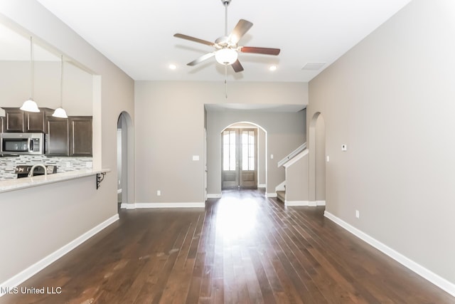 unfurnished living room featuring arched walkways, a ceiling fan, dark wood-style flooring, and recessed lighting