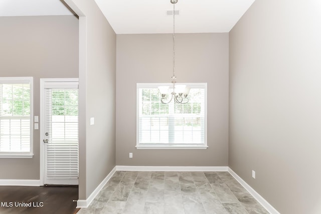 unfurnished dining area featuring a chandelier and baseboards