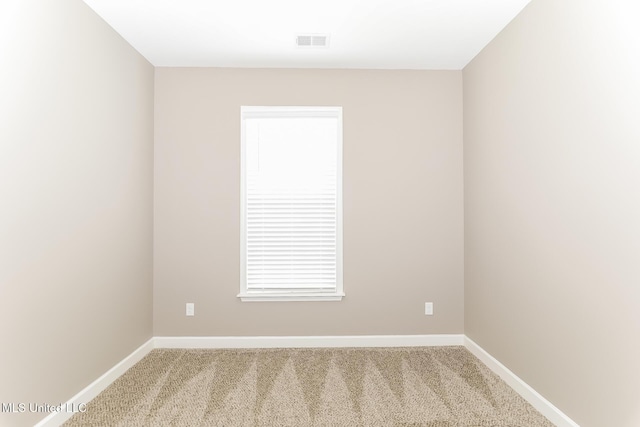 spare room featuring light carpet and baseboards