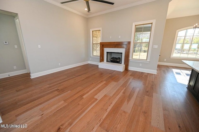 unfurnished living room with ceiling fan, light hardwood / wood-style floors, a wealth of natural light, and a brick fireplace