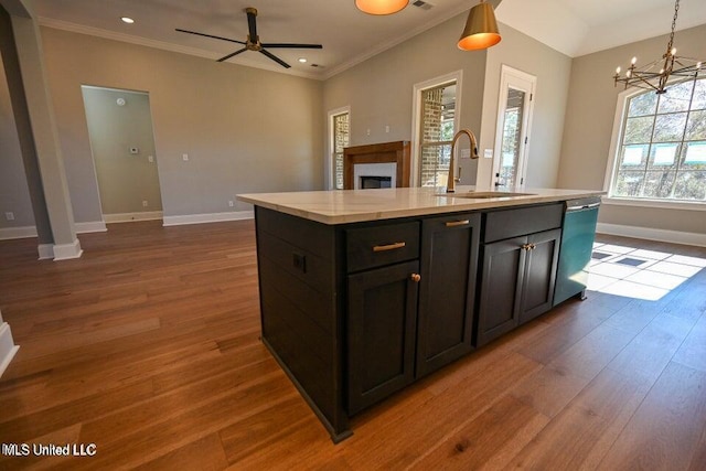 kitchen featuring ceiling fan with notable chandelier, sink, pendant lighting, dishwasher, and an island with sink