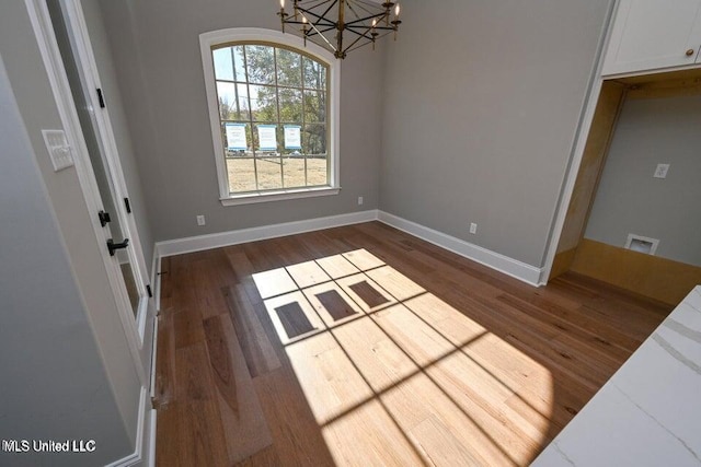 unfurnished dining area with dark hardwood / wood-style floors and a notable chandelier