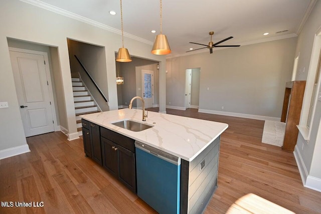 kitchen featuring light stone counters, stainless steel dishwasher, sink, a center island with sink, and hanging light fixtures