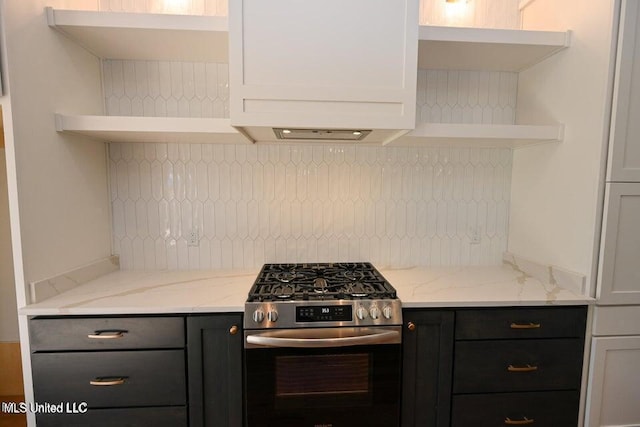 kitchen featuring white cabinets, high end stove, light stone counters, and backsplash