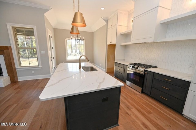 kitchen with pendant lighting, white cabinets, a center island with sink, sink, and stainless steel gas range