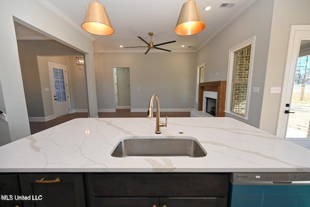 kitchen with light stone countertops, dishwasher, sink, ceiling fan, and hanging light fixtures