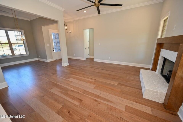 unfurnished living room featuring a fireplace, wood-type flooring, ceiling fan with notable chandelier, and ornamental molding