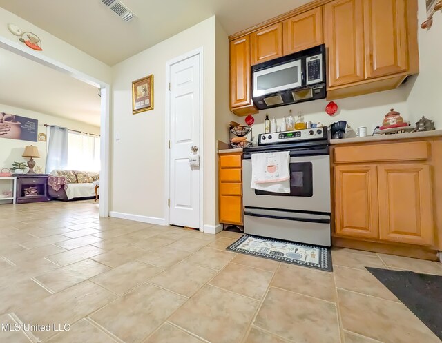 2220 18th Ave, Gulfport, MS 39501 - kitchen with visible vents, black microwave, stainless steel electric range oven, light tile patterned floors, and light countertops