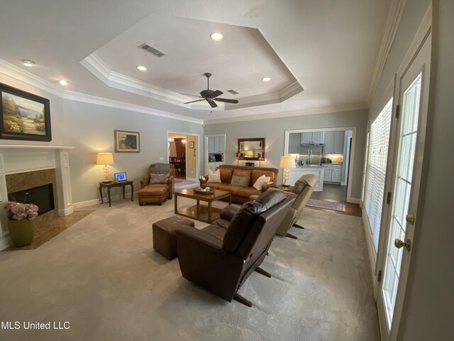 living room with crown molding, visible vents, a ceiling fan, and a high end fireplace