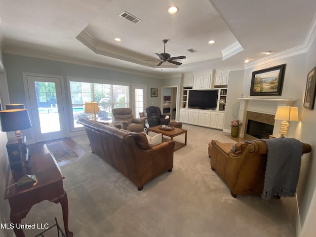 living room featuring a raised ceiling, crown molding, visible vents, and plenty of natural light