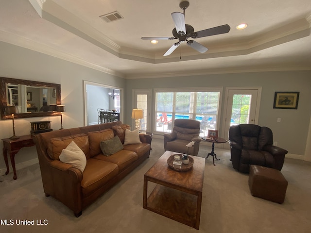 living room featuring visible vents, ceiling fan, a tray ceiling, and carpet