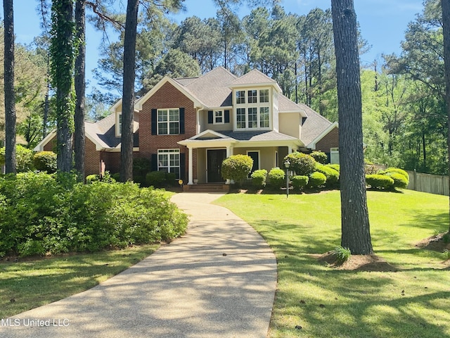 craftsman-style house with a front yard, a shingled roof, and brick siding