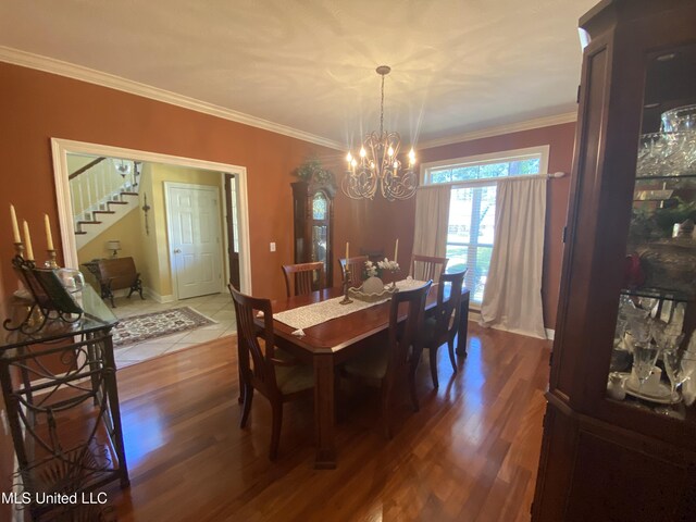 dining area with crown molding, wood finished floors, an inviting chandelier, and stairway
