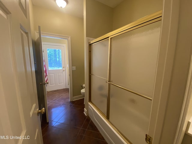 bathroom featuring toilet, enclosed tub / shower combo, and tile patterned flooring