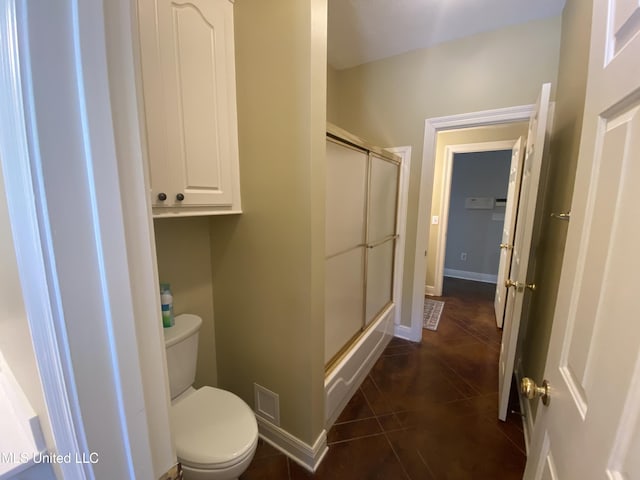 bathroom featuring toilet, tile patterned floors, and a shower with door