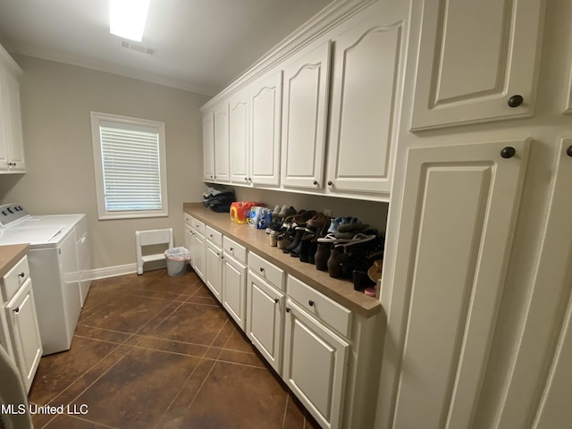 washroom with dark tile patterned floors, baseboards, visible vents, washer and clothes dryer, and cabinet space