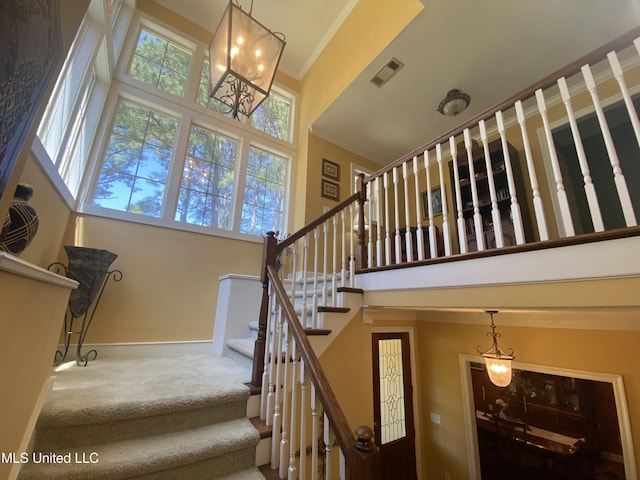 stairs with baseboards, carpet flooring, a towering ceiling, and visible vents