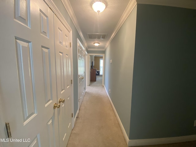 hallway featuring light carpet, visible vents, baseboards, and crown molding