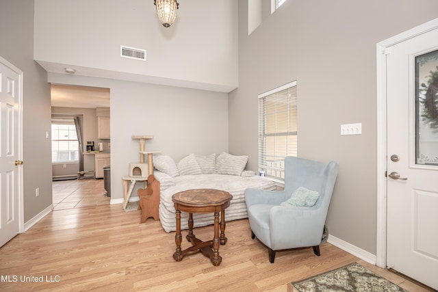 living room featuring light hardwood / wood-style flooring and a towering ceiling