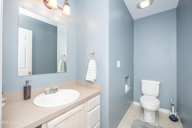 bathroom featuring toilet, vanity, a textured ceiling, and tile patterned floors