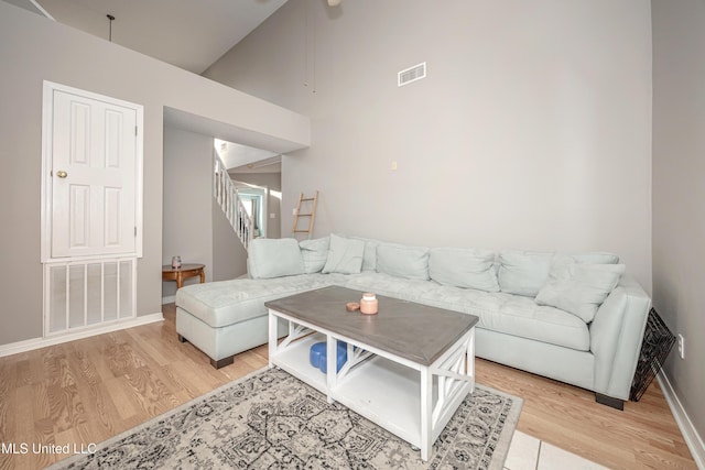 living room featuring high vaulted ceiling and light hardwood / wood-style flooring