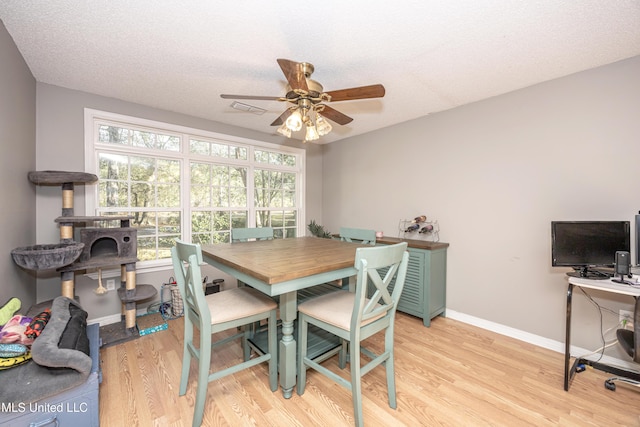 dining room featuring a textured ceiling, light hardwood / wood-style flooring, a wealth of natural light, and ceiling fan