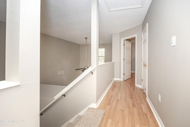 corridor featuring light hardwood / wood-style flooring and a textured ceiling