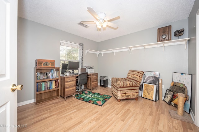 office featuring a textured ceiling, light wood-type flooring, and ceiling fan