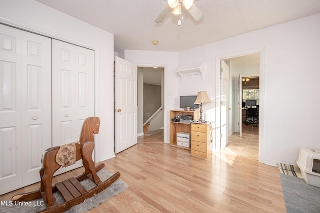 sitting room with ceiling fan, light wood-type flooring, and a textured ceiling