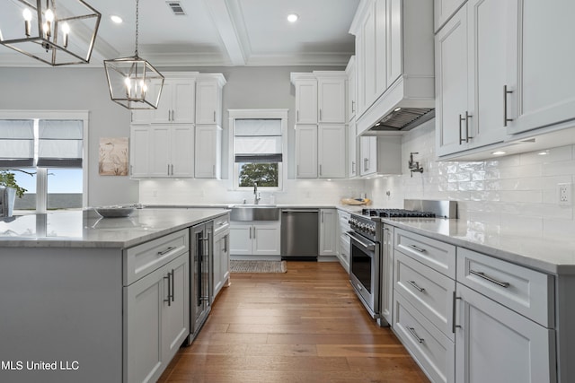 kitchen featuring custom range hood, hanging light fixtures, appliances with stainless steel finishes, and white cabinets