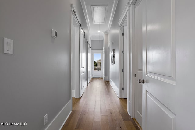 hall featuring crown molding, a barn door, and hardwood / wood-style floors