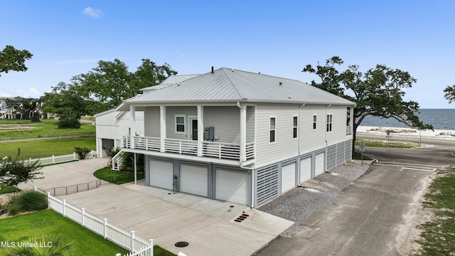 rear view of property with a yard, a garage, and a water view