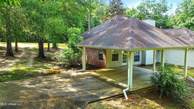 129 E Sunnybrook Rd, Carriere, MS 39426 - back of house featuring a chimney, roof with shingles, a carport, concrete driveway, and brick siding