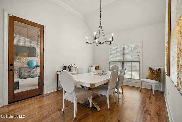 dining area featuring lofted ceiling, a notable chandelier, baseboards, and wood finished floors