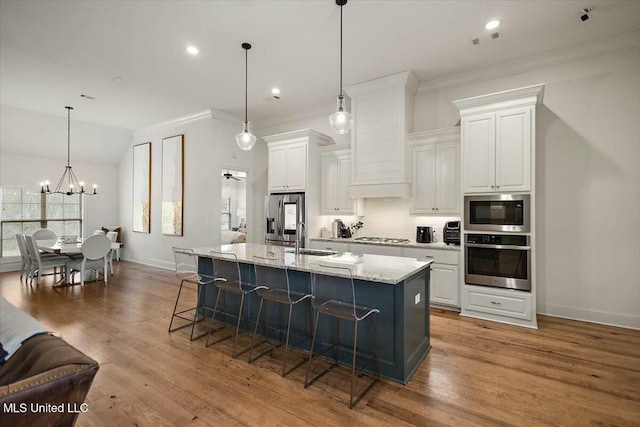 kitchen with white cabinetry, a kitchen bar, appliances with stainless steel finishes, and a sink