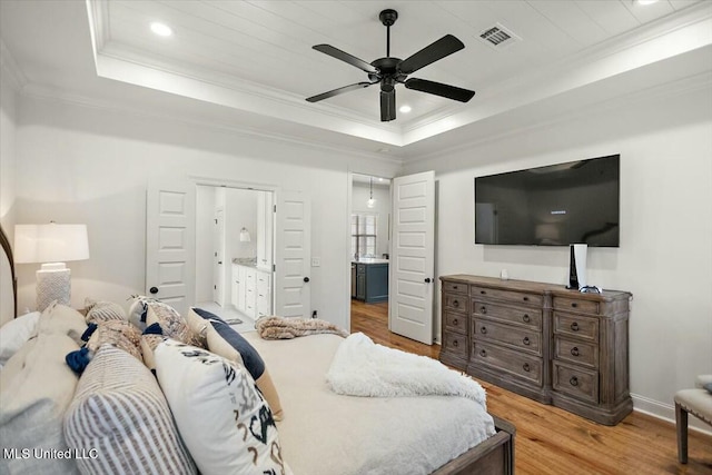 bedroom with visible vents, connected bathroom, wood finished floors, a tray ceiling, and crown molding