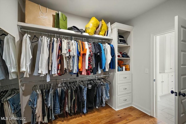 walk in closet with wood finished floors