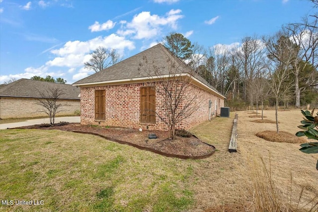 view of home's exterior with central air condition unit, a yard, roof with shingles, and brick siding