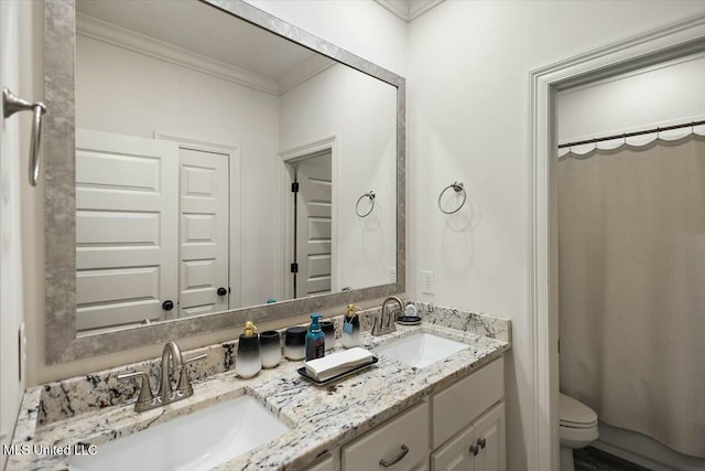 bathroom featuring crown molding, a sink, toilet, and double vanity